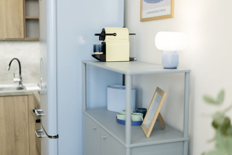 Kapslový kávovar a designová lampa na komodě